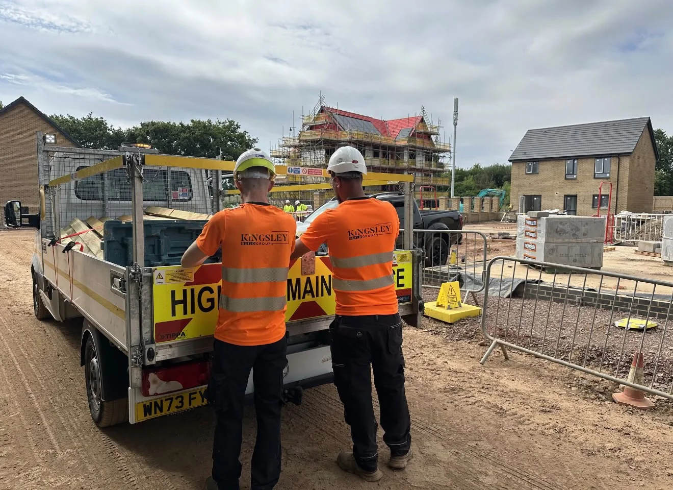 Two Kingsley operatives in Kingsley hi-vis beside a highway maintenance truck on a housing site