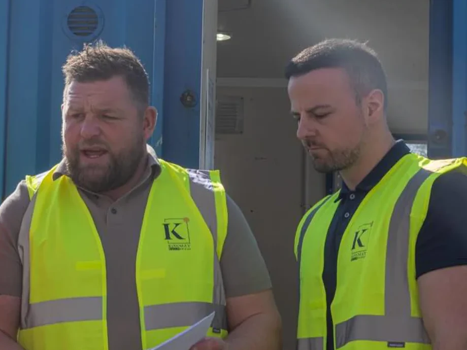 Two Kingsley team members in Kingsley hi-vis at a site briefing beside the welfare unit