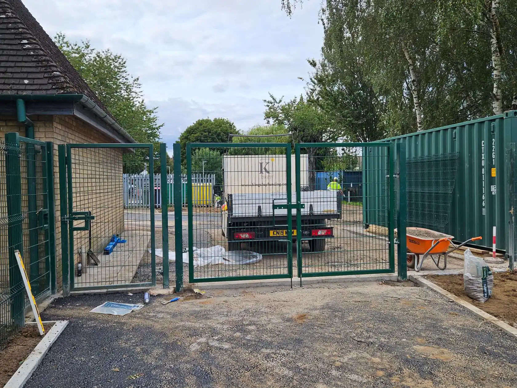 Green mesh fencing and double gates around a utility compound, Kingsley truck behind