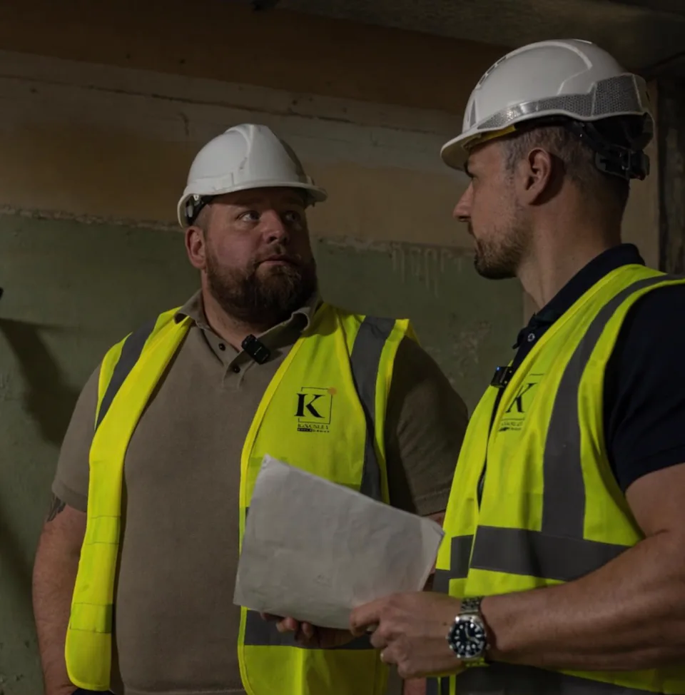 Two Kingsley managers in hard hats reviewing drawings on site