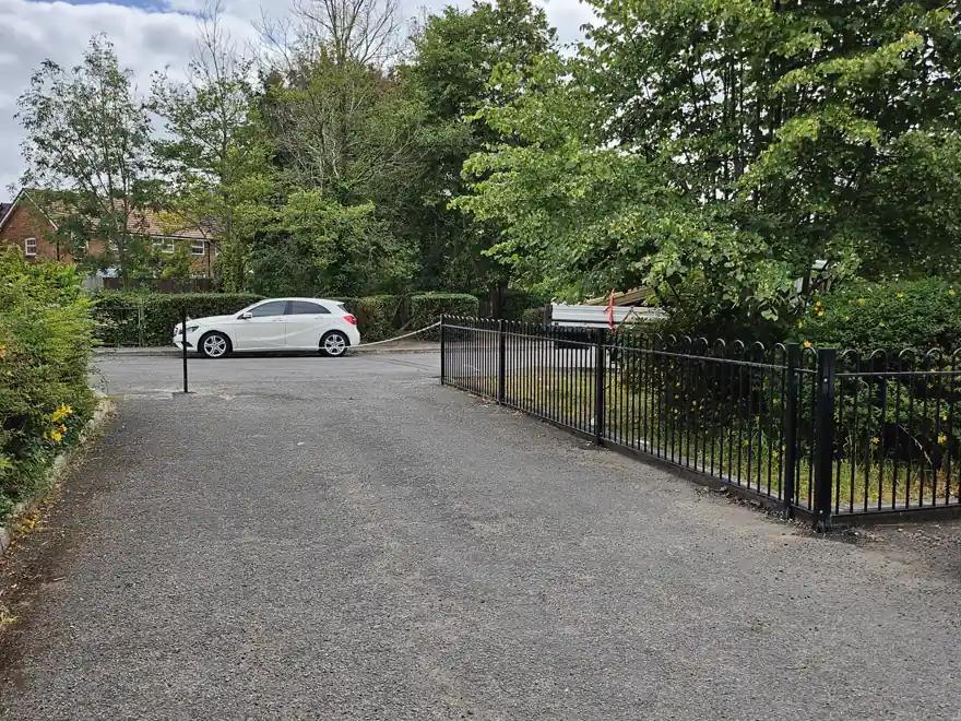 Black bow-top railings along a car-park drive in Newport