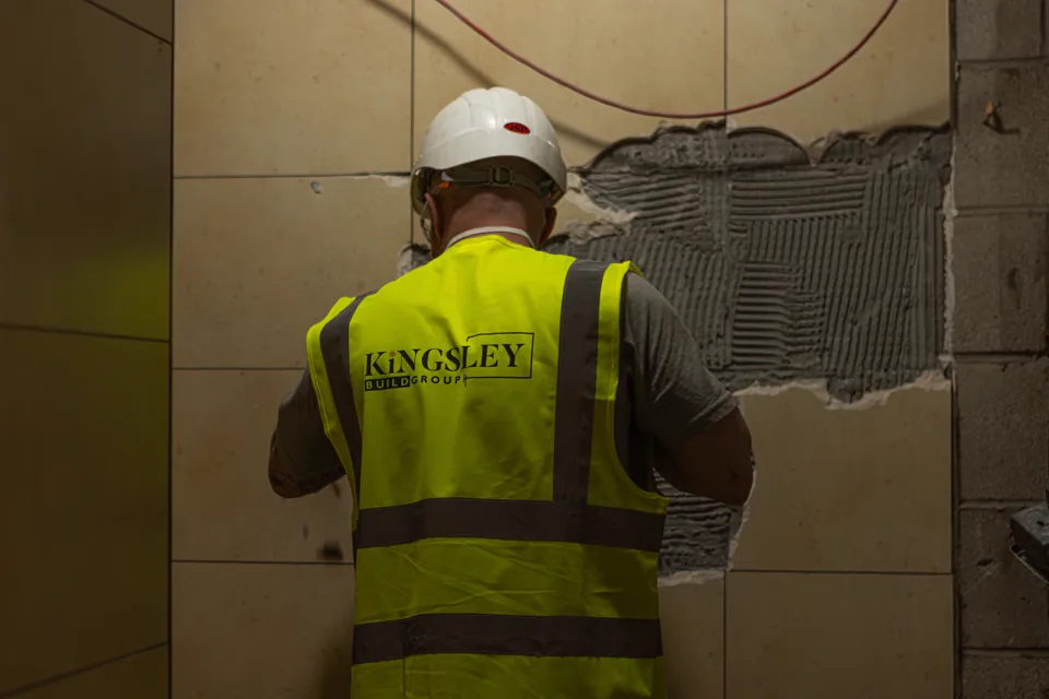 Kingsley operative re-tiling an interior wall