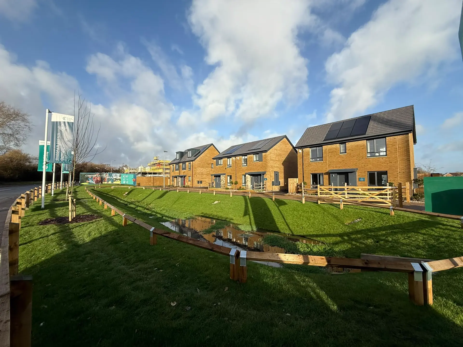 New homes behind a turfed swale and timber knee-rail at a Cardiff development